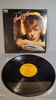 Original David Bowie Young Americans vinyl record album with cover showing close-up photo of Bowie, propped in background with vinyl record in foreground.