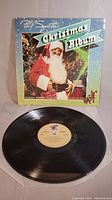 Photo of Phil Spector Christmas Album vinyl record and original cover featuring Santa Claus in Christmas setting.