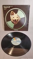 Photo of vinyl record in front of sleeve showing front cover design with wolf head graphic and condition of cover and vinyl disc.