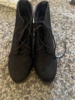 Top view of both black suede-like ankle boot heels showing round toes and lace-up fronts.