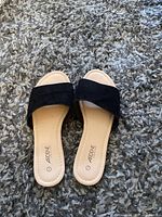 Pair of black slide sandals with wide strap, beige footbed, size 7, Ardene brand, laid on a gray textured carpet.
