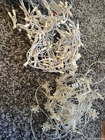 Two tangled sets of white wired Christmas lights, one with standard small bulbs, one with star/snowflake shaped bulbs.