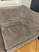 Close-up of corner piece showing soft gray upholstery with stitched and tufted cushions