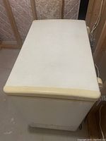 Exterior view of the white deep freezer showing top lid and yellow trim.