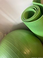 Close-up shot of the green gym ball and rolled yoga mat showing texture and color.