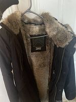 Front view of TNA jacket on hanger showing faux fur lining and collar