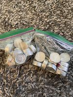 Two clear ziplock bags filled with white tea light candles with silver metal holders.