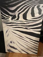 Close-up photo of a zebra painting showing black and white stripes and details of the zebra's fur and eye area.