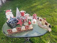Table display of mixed Christmas decorations and mugs on grass background