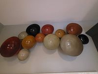View of 13 decorative bowl-shaped wall hangings in an array of colors and sizes arranged on the floor