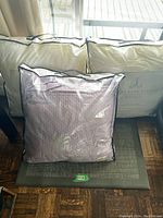 Three pillows packaged, two white in Au Lit Fine Linens Esprit branded cases, one lavender textured pillow in clear plastic.