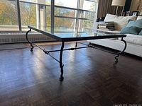 Glass top coffee table with metal legs in good condition, showing glass surface and metal frame design