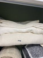 Folded stacked blankets/linens in cream and white colors