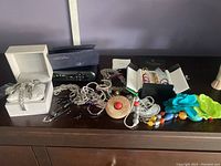 Overview of costume jewelry including chain belt, flower pins, necklaces, watches, and pen on surface