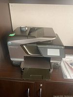 Photo of HP OfficeJet Pro 8600 Plus multifunction printer showing front and paper tray with touchscreen panel.