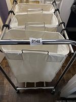 Front view of the rolling laundry basket showing three canvas sorting bags attached to the metal frame.