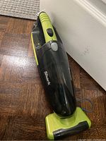 Full view of the Shark cordless handheld vacuum cleaner showing green and black body with handle and dust container.