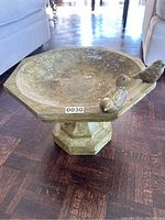 Direct angled view showing the concrete bird bath with two bird figures on the rim and the bowl interior.