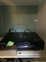 Side angle showing full stereo unit and attached cables on shelf.