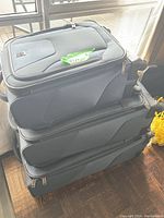 Stacked set of three gray Travelpro suitcases, largest on bottom, smallest on top, showing side profile with zipper and wheels visible.