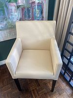 Front view of one white real leather dining chair showing padded seat and armrests
