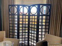 Full view of the four-panel folding wooden screen with geometric cut-outs arranged around a balcony area.