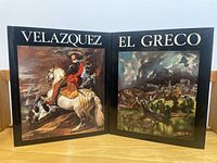 Two art books standing upright side by side showing front covers; Velázquez on left, El Greco on right.