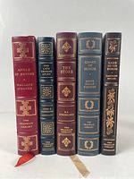 Five Franklin Library leather bound books standing upright showing spine details. Titles include Angle of Repose, The Late George Apley, The Store, Guard of Honor, Lamb in His Bosom.