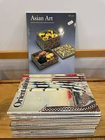 Stack of 25 magazines shown with Orientations magazines on top and one Asian Art magazine standing upright showing the cover with decorative boxes.