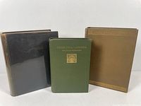 Three vintage hardcover travel books shown in a row seen from the front cover and front edges. Book covers are dark brown, tan, and olive green with decorative designs.