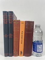Five military history books shown upright with a water bottle for scale.