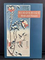 Front cover of the hardcover art book showing a woodblock print of birds and flowers with title text.