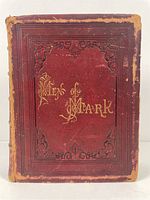 Front cover of the book showing red leather with gold embossed title and decorative borders, leather worn at edges and corners.