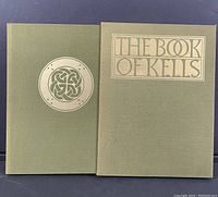 Front view of hardcover book and matching slipcase, both olive green with gold embossed designs and title.
