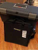 Grey and red Rubbermaid toolbox with handle and black Omnigrid carrying case underneath.