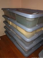 Stacked large translucent plastic bins with gray lids for storing fabric