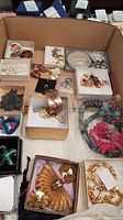 Full view of assorted jewelry in a box showing the variety of items including pearl earrings, copper bracelet, colorful beads necklace and more.