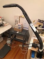 Full view of black OttLite task lamp with flexible neck and clamp base on desk.