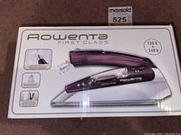 Box front showing Rowenta First Class travel iron with features image and voltage info.