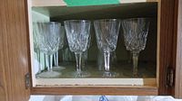 Twelve Waterford crystal wine glasses in cabinet, showing general quantity and setting.