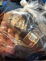 Multiple yarn skeins in a clear plastic bag showing different colors and brands including Bernat and Patons.