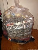 Full clear bag containing all six yarn skeins on hardwood floor