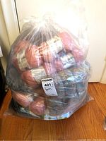Large clear plastic bag filled with multiple pink yarn skeins and some gray mixed yarn skeins tightly packed.