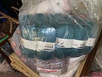 Bag of teal yarn skeins labeled Laine Merino Wool, sheep logo visible