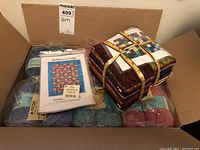 Overview of box contents showing multiple Patons yarn skeins, a quilting pattern, and fabric bundle