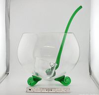 Photo of the entire punchbowl with ladle, showing green swirl feet base and clear glass body with ladle resting inside.