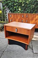 Front view of one nightstand showing overall design, wood finish, drawer pull and open shelf