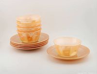 Full set of 5 peach lustre custard cups stacked on 5 matching saucers, one cup and saucer separated and displayed at front