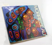 Front cover of the hardcover art book featuring colorful Ojibway inspired faces artwork by Norval Morrisseau with 'Morrisseau' text on side.
