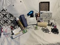 Full view of lot contents, including shower curtain sections, hair dryer, makeup case, nail polish, hair ties and other accessories.